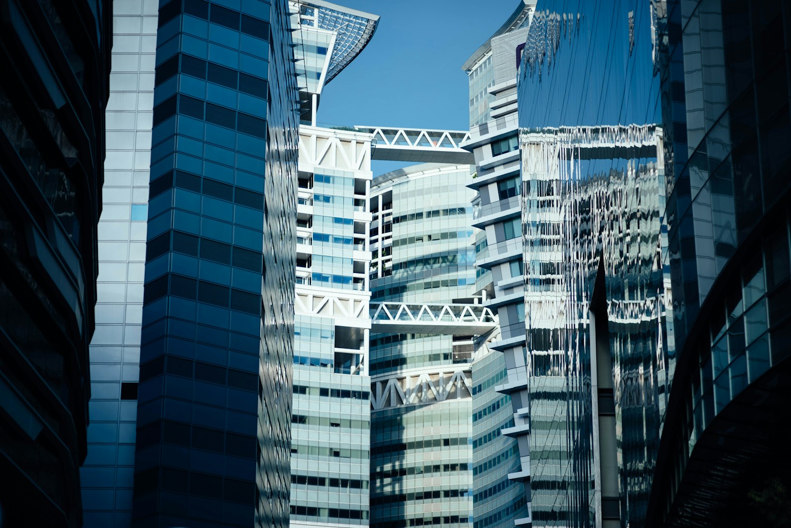 Blue glass office towers with connecting structures seen between neighboring buildings.